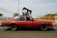 A car drives past in front of an oil pump in Lagunillas, Ciudad Ojeda, in the state of Zulia, Venezuela, March 18, 2015. REUTERS/Isaac Urrutia