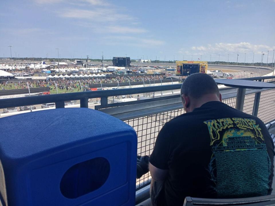 A fan looks out at the Vortex Stage from a shaded patio on the west end of Daytona International Speedway's grandstand concourse on Saturday, May 11, 2024.