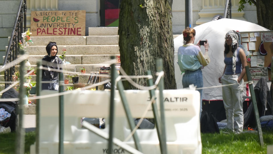 A person uses a mobile device to record a person wearing a keffiyeh, right, near the remnants of an encampment of tents in Harvard Yard, on the campus of Harvard University, Tuesday, May 14, 2024, in Cambridge, Mass. Anti-war protesters have taken down their tents in Harvard Yard after the university agreed to meet to discuss their demands. The student protest group calling themselves Harvard Out of Occupied Palestine say their camp "outlasted its utility." (AP Photo/Steven Senne)