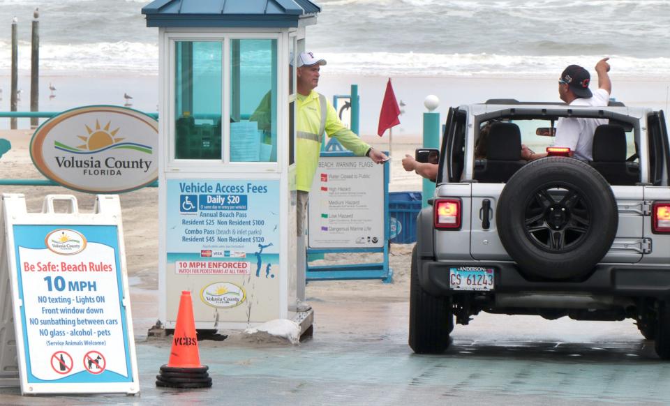 A beach tollbooth attendant talks with visitors as they pay the toll, Tuesday, December 14, 2021, at the International Speedway Boulevard beach ramp.