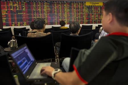 Thai investors sit in front of an electronic board displaying live market data at a stock broker's office in central Bangkok, Thailand, August 24, 2015. REUTERS/Athit Perawongmetha/Files