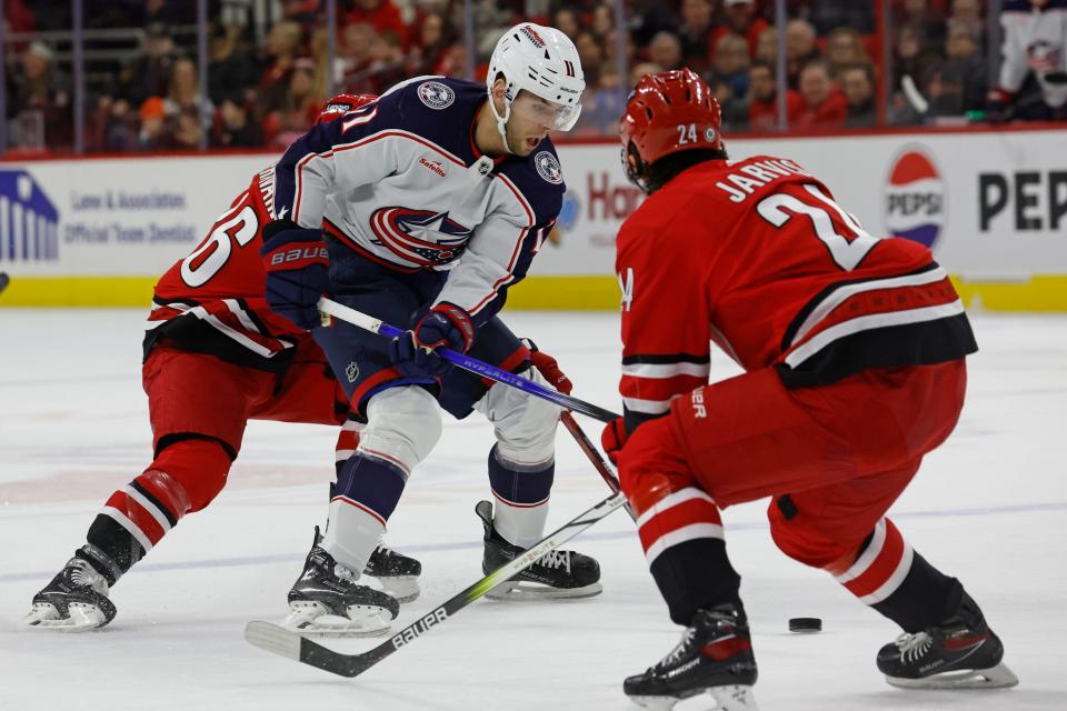 Columbus Blue Jackets' Adam Fantilli (11) controls the puck between Carolina Hurricanes' Teuvo Teravainen (86) and Seth Jarvis (24) during the first period of an NHL hockey game in Raleigh, N.C., Sunday, Nov. 26, 2023. (AP Photo/Karl B DeBlaker)