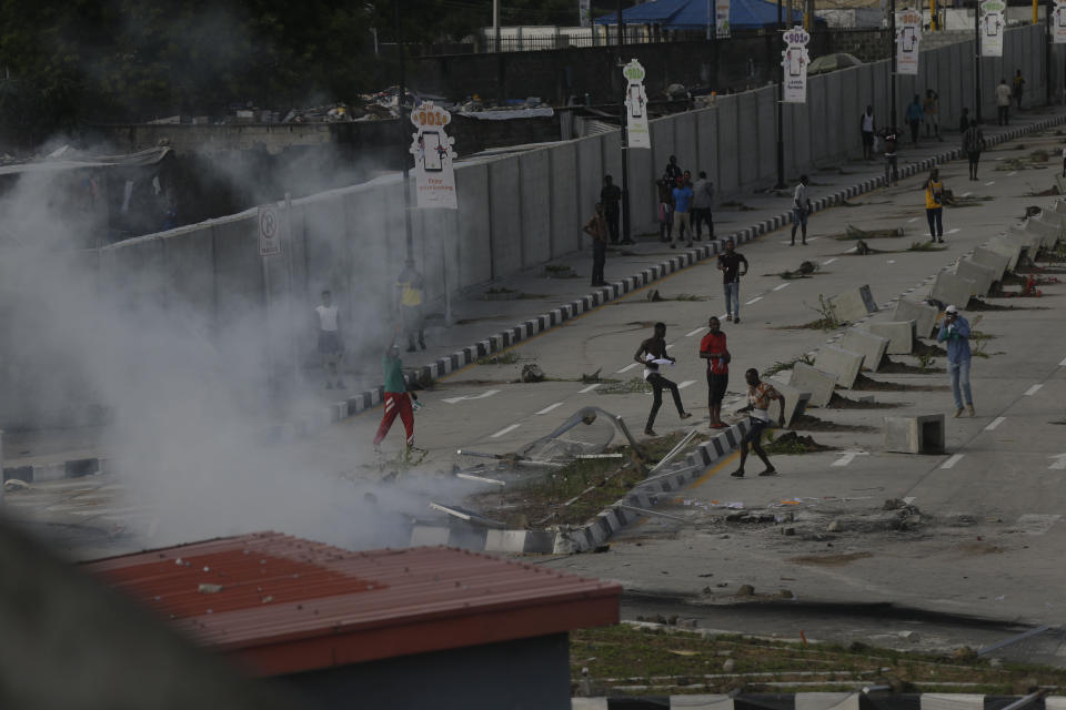 Manifestantes escapan mientras agentes de la policía emplean gases lacrimógenos para dispersar una protesta contra la brutalidad policial el 21 de octubre de 2020, en Lagos, Nigeria. (AP Foto/Sunday Alamba)