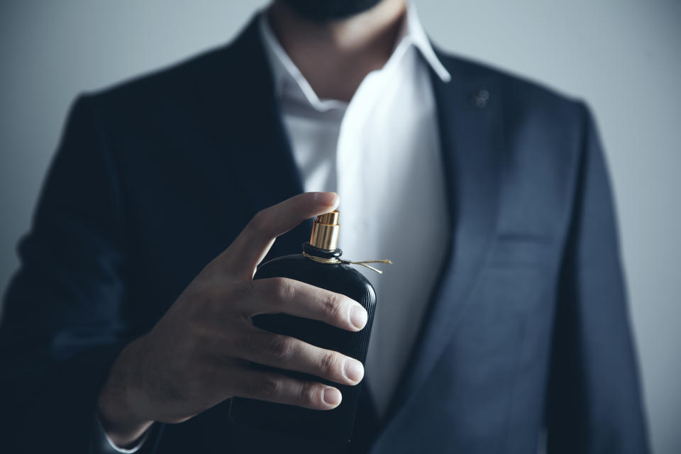 Handsome young man using perfume