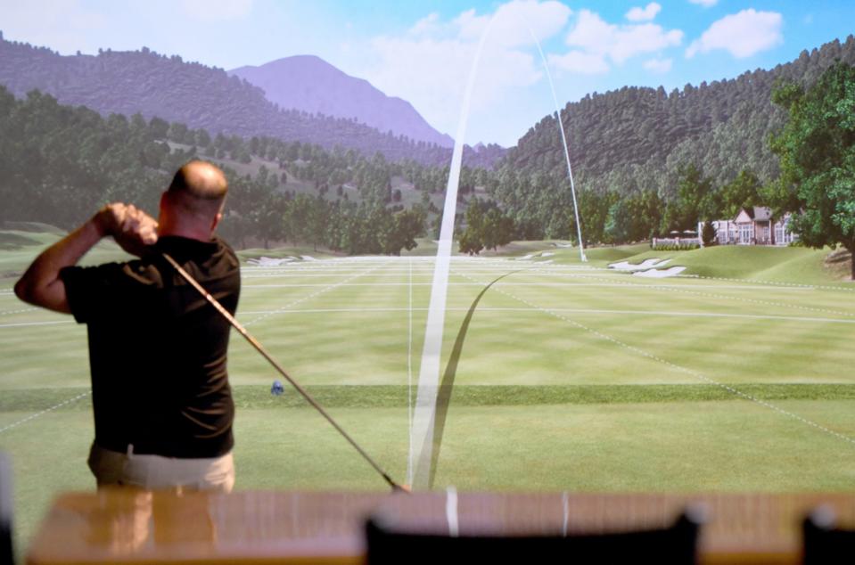 Jared Clark, co-owner of The 19th Hole in downtown Canton, takes a swing on a golf simulator. Virtual golf has increased in popularity both in Stark County and across the state and country.