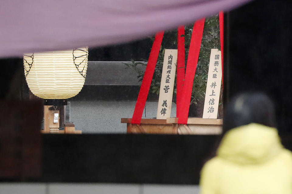 A visitor stands near religious ornaments at the Yasukuni Shrine in Tokyo Saturday, Oct. 17, 2020. While Japan’s new Prime Minister Yoshihide Suga’s own personal ideology is unknown, he followed his former boss Shinzo Abe's example in making ritual donations of religious ornaments Saturday to the Yasukuni Shrine to pay respect to the war dead. A sign, left, reads "Prime Minister Yoshihide Suga." (Masanori Kumagai/Kyodo News via AP)