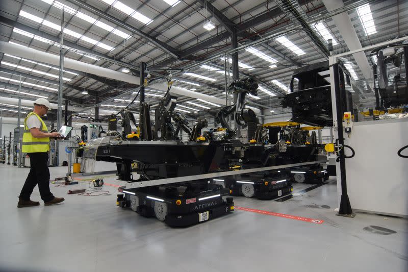 An engineer at electric van maker Arrival watches as autonomous robots move parts for a prototype vehicle at the company's factory in Bicester