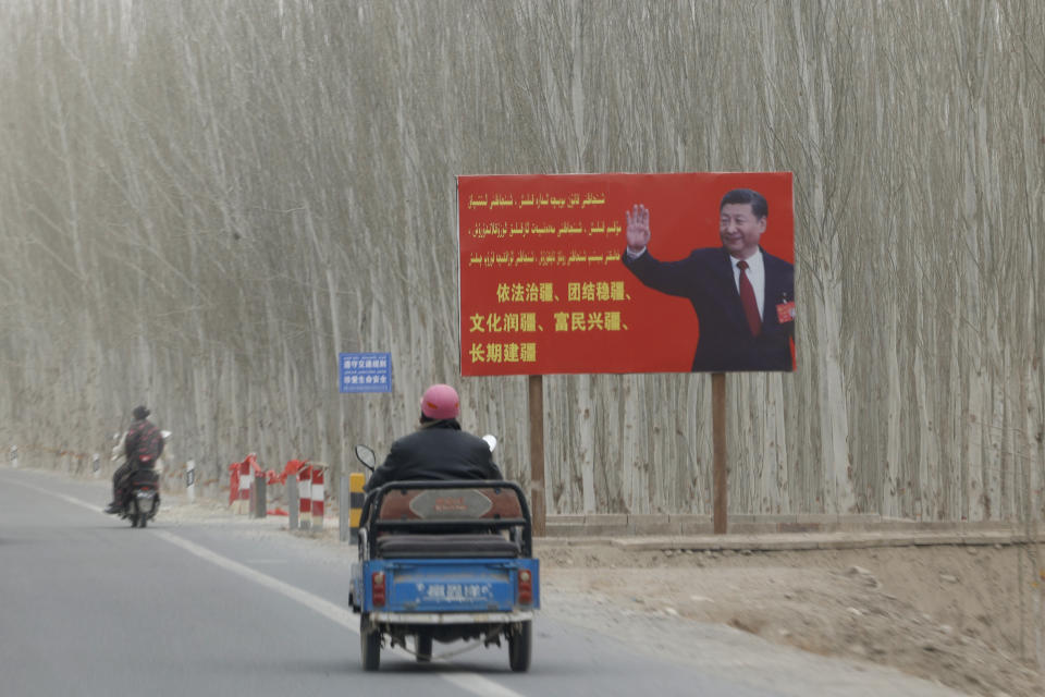 Chinese President Xi Jinping is seen on a billboard with the slogan, "Administer Xinjiang according to law, unite and stabilize the territory, culturally moisturize the territory, enrich the people and rejuvenate the territory, and build the territory for a long term," in Yarkent County in northwestern China's Xinjiang Uyghur Autonomous Region on March 21, 2021. Four years after Beijing's brutal crackdown on largely Muslim minorities native to Xinjiang, Chinese authorities are dialing back the region's high-tech police state and stepping up tourism. But even as a sense of normality returns, fear remains, hidden but pervasive. (AP Photo/Ng Han Guan)