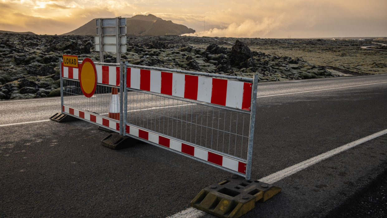  In the center of a road a red and white road blockage blocks the path to the Blue lagoon. 