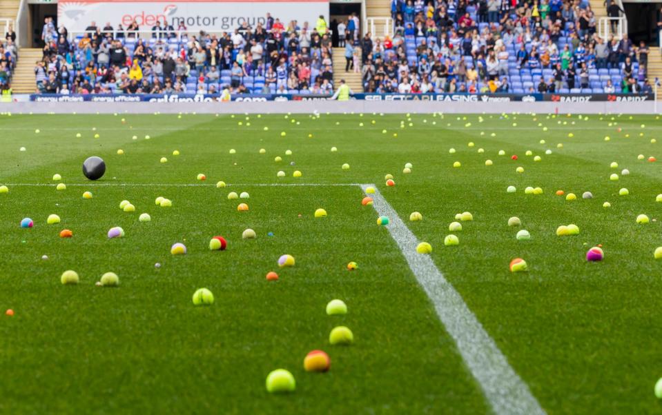 Readers throw tennis balls onto the field in protest against their owner