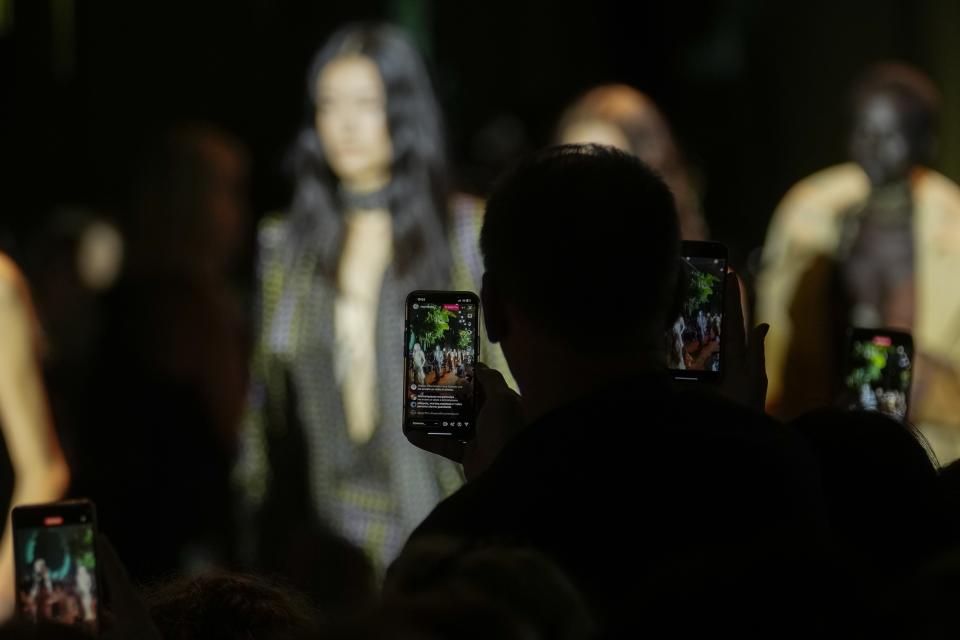 Guests use their cell phones to record the Roberto Cavalli women's Spring Summer 2024 collection presented in Milan, Italy, Wednesday, Sept. 20, 2023. (AP Photo/Luca Bruno)