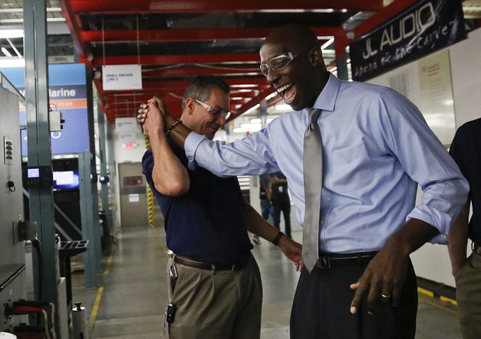 Miramar Mayor Wayne Messam, right, laughs with Stephen Turrisi, left, the director of training and technical services at JL Audio during a tour in Miramar, Fla. (Photo credit: Brynn Anderson)