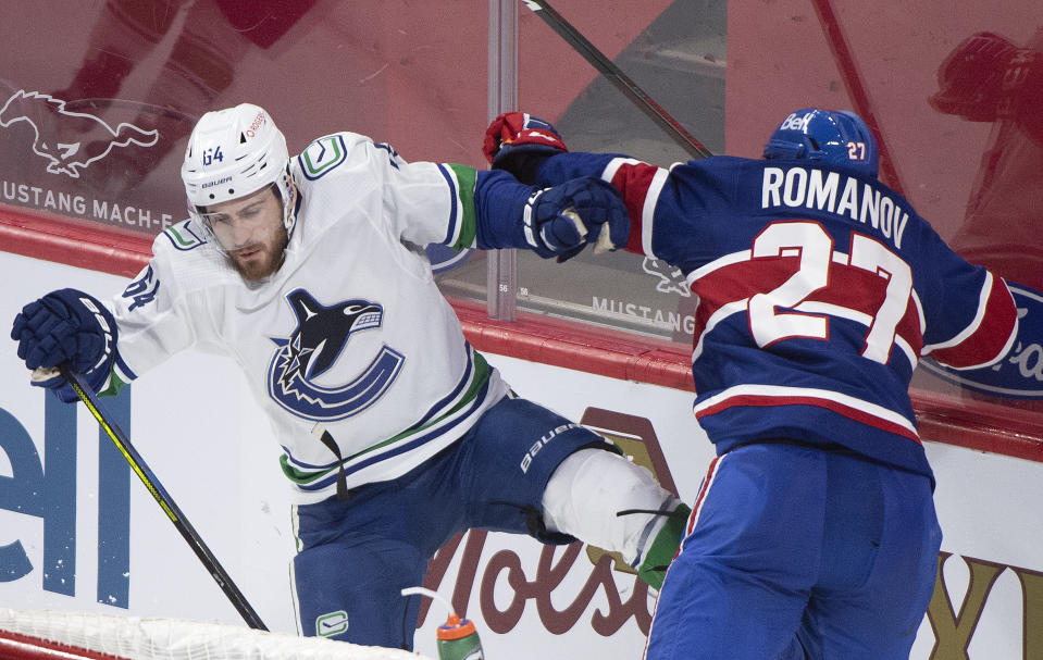 Montreal Canadiens' Alexander Romanov (27) collides with Vancouver Canucks' Tyler Motte during the first period of an NHL hockey game in Montreal, Quebec, Saturday, March 20, 2021. (Graham Hughes/The Canadian Press via AP)