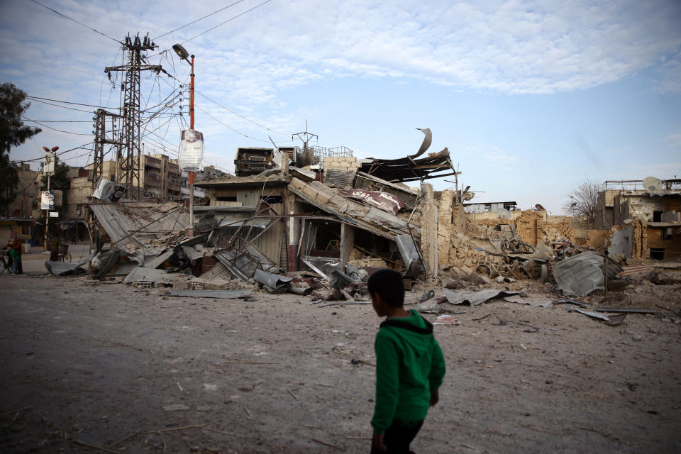 A child walks near damaged buildings in the besieged town of Douma, Syria, on Feb. 20, 2018. (Photo: Bassam Khabieh / Reuters)