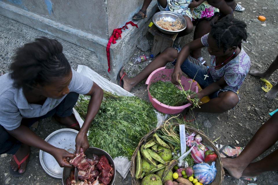 In this Dec. 3, 2019 photo, street vendors ready ingredients to make soup to sell in the Cite Soleil slum of Port-au-Prince, Haiti. Disruption caused by recent protests, combined with rising commodity prices and the depreciation of the Haitian gourde against the US dollar, has reduced the ability of Haiti's poorest to buy food. (AP Photo/Dieu Nalio Chery)