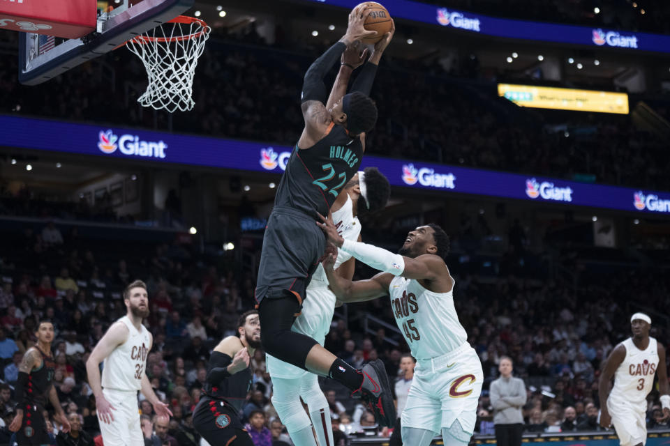 Washington Wizards forward Richaun Holmes (22) grabs a rebound to shoot against Cleveland Cavaliers defenders during the first half of an NBA basketball game in Washington, Sunday, Feb. 25, 2024. (AP Photo/Manuel Balce Ceneta)