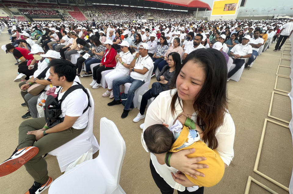 A woman carries her baby as she waits with other faithful to attend a Holy Mass that will be held by Pope Francis at Bahrain National Stadium in Manama, Bahrain, Saturday, Nov. 5, 2022. Pope Francis is making the Nov. 3-6 visit to participate in a government-sponsored conference on East-West dialogue and to minister to Bahrain's tiny Catholic community, part of his effort to pursue dialogue with the Muslim world. (AP Photo/Hussein Malla)