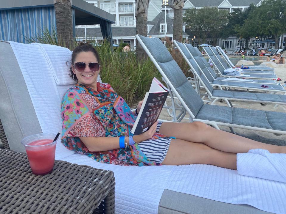 kari reading a book on a day bed near a private cabana at disney's yacht club