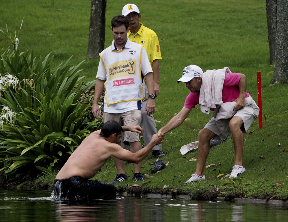 Pablo Larrazabal, left, of Spain, is pulled out of a lake after being attacked by a swarm of hornets during the second round of the Malaysian Open golf tournament at Kuala Lumpur Golf and Country Club in Kuala Lumpur, Malaysia, Friday, April 18, 2014. (AP Photo/Joshua Paul)