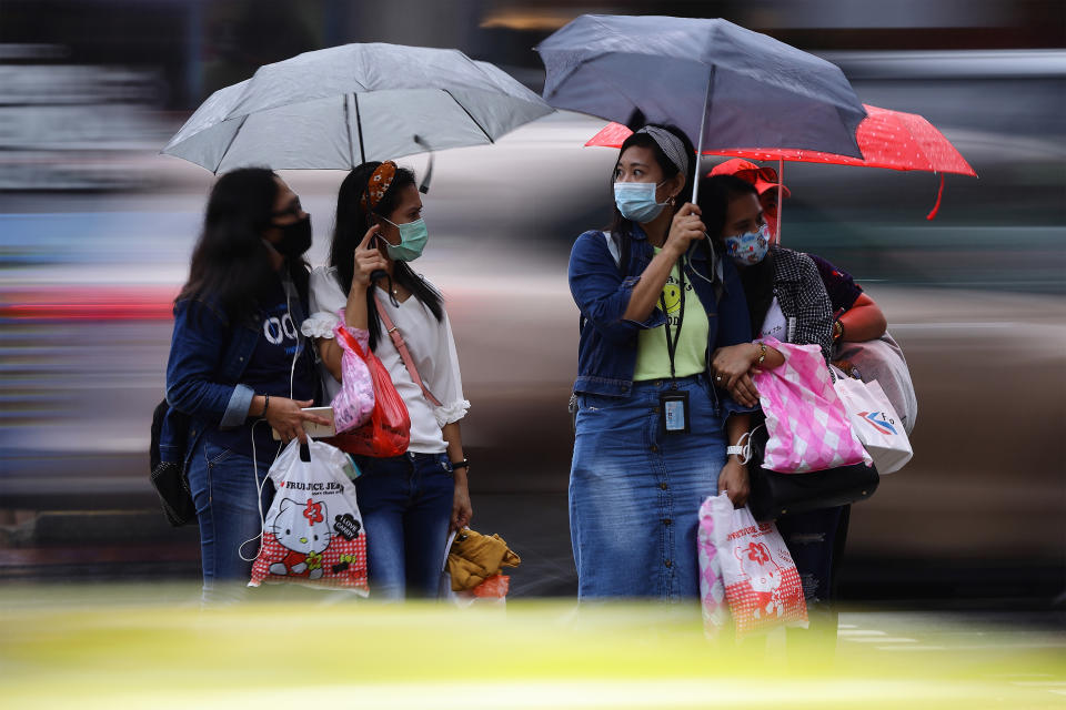 People seen waiting in the rain to cross a street in Singapore on 10 January. (PHOTO: Getty Images)