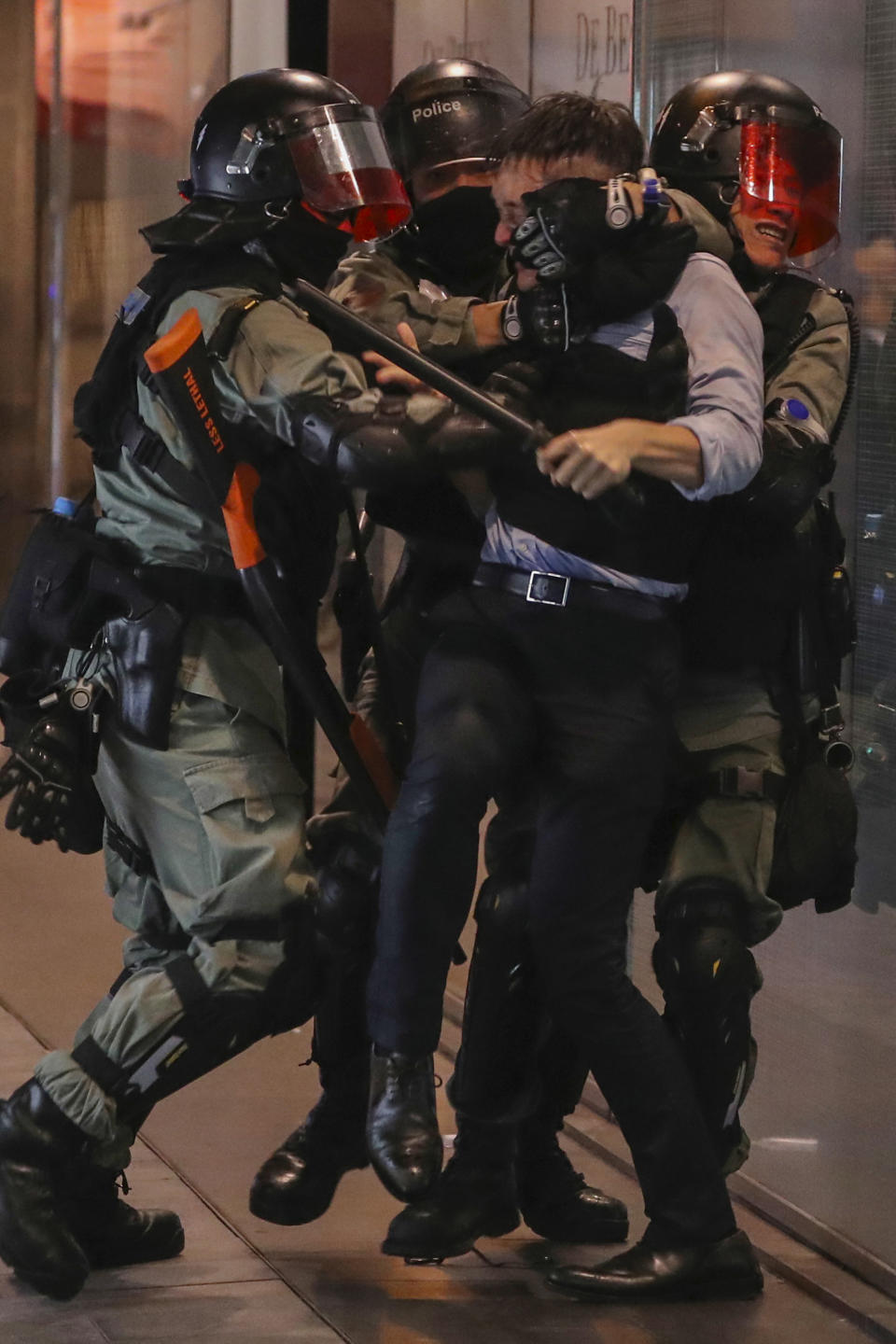 Riot police detain a man in Central in Hong Kong, Tuesday, Nov. 12, 2019. Police and protesters battled outside university campuses and several thousand demonstrators blocked roads as they took over a central business district at lunchtime on Tuesday in another day of protest in Hong Kong. (AP Photo/Ng Han Guan)