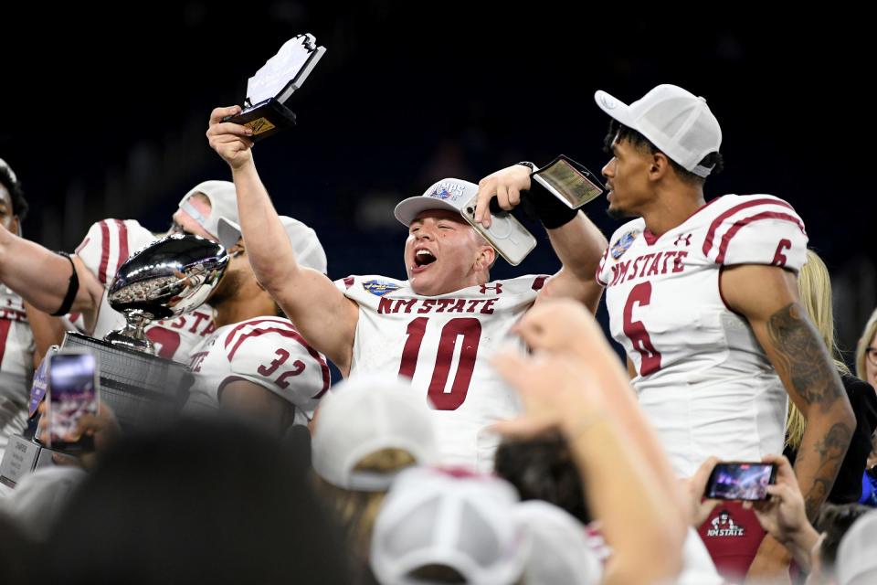 New Mexico State quarterback Diego Pavia shows off his game MVP trophy as he and his teammates celebrate after 24-19 win over Bowling Green in the Quick Lane Bowl on Monday, Dec. 26, 2022, at Ford Field.