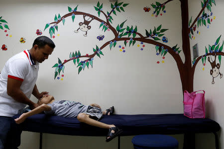 Miguel Anton (L) comforts his son Jose Gregorio Anton, 11, a neurological patient being treated with anticonvulsants, after a blood test at a clinic in La Guaira, Venezuela February 20, 2017. REUTERS/Carlos Garcia Rawlins