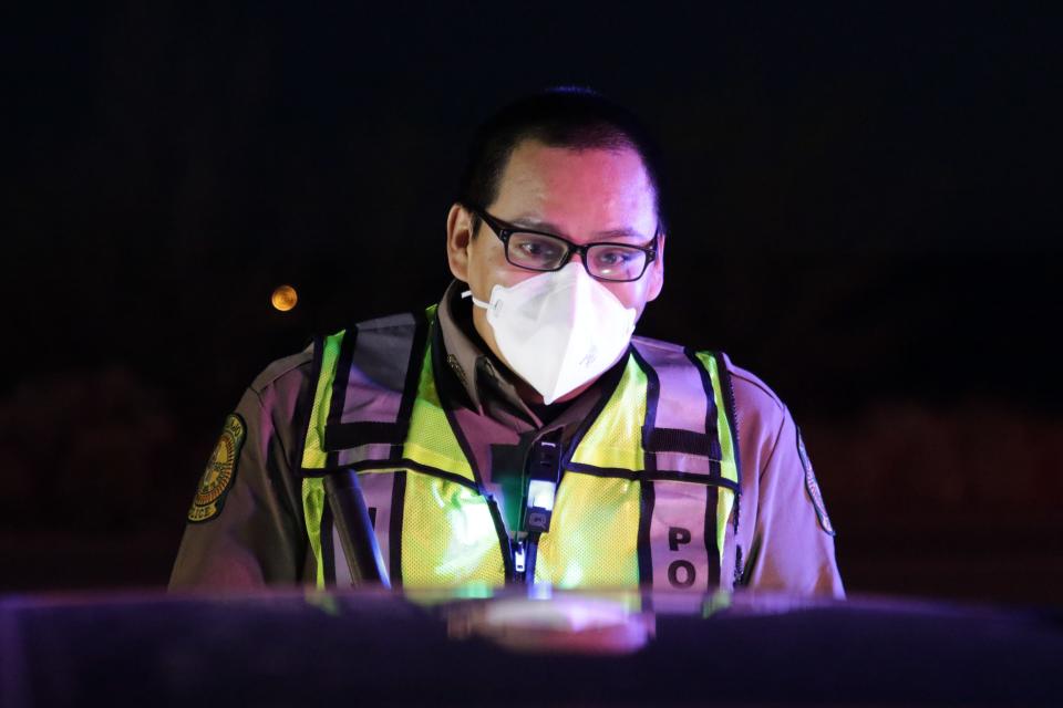 Navajo Police Officer Brandon Jim reminds a motorist about the nightly curfew for the Navajo Nation during a police checkpoint on April 1 on U.S. Highway 64 in Hogback.