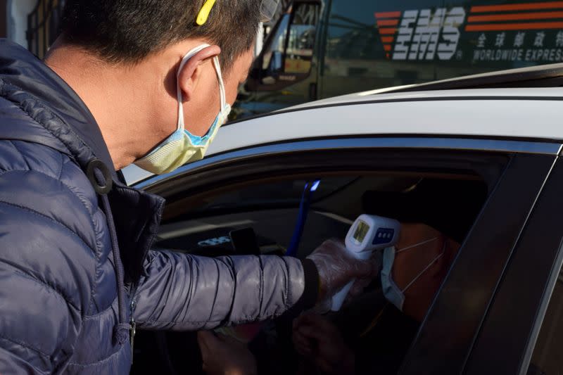 Volunteer measures the body temperature of a driver in Suifenhe