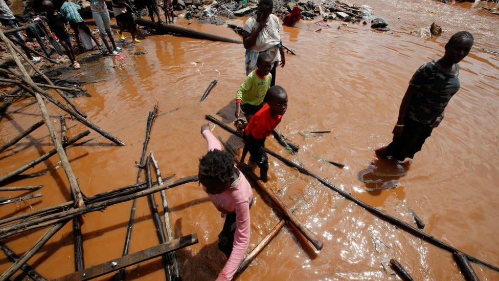 Residents wade through flood waters after the Nairobi river burst its banks and destroyed their homes within the Mathare valley settlement in Nairobi, Kenya April 24, 2024