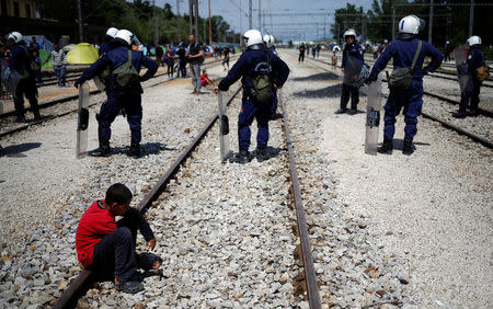 A boy sits on the rail tracks as Greek police arrives to intervene during a scuffle which started at a food distribution queue, at a makeshift camp for migrants and refugees at the Greek-Macedonian border, near the village of Idomeni, Greece, April 22, 2016. REUTERS/Stoyan Nenov