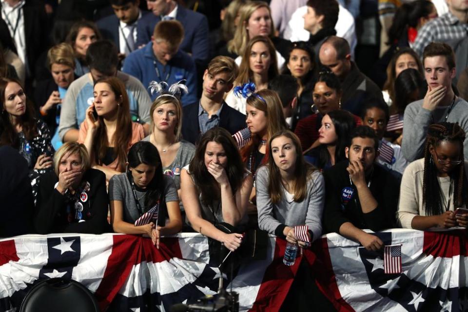 crowd looks dismayed behind american flag bunting