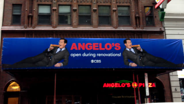 Those walking past New York City's Ed Sullivan Theater got a slice of comedy thanks to Stephen Colbert's temporary <em>Late Show</em> marquee. In anticipation of Colbert's debut on the late-night CBS program, a sign was put up to promote Angelo's Pizza, which is located next door to the studio. <strong> WATCH: Stephen Colbert Responds to Gwen Stefani Flubbing His Name </strong> The ad shows Colbert eating pizza with the message: "Angelo's open during renovations." ETONLINE Talk about prime ad space! This is after all the marquee location that once announced The Beatles first televised American appearance. . This is just one of many stunts Colbert has pulled off in lead-up to his new hosting gig. Just last week, he hosted a public access show in Monroe, Mich. and interviewed rapper Eminem. <strong> WATCH: Stephen Colbert Attempts a New <em>Late Show</em> Theme Song </strong> Also last month, Colbert nailed an impersonation of country crooner Toby Keith at the Songwriters Hall of Fame. The <em>Late Show with Stephen Colbert</em> premieres September 8. In the meantime, relive some of the best moments from David Letterman's last <em>Late Show:</em>