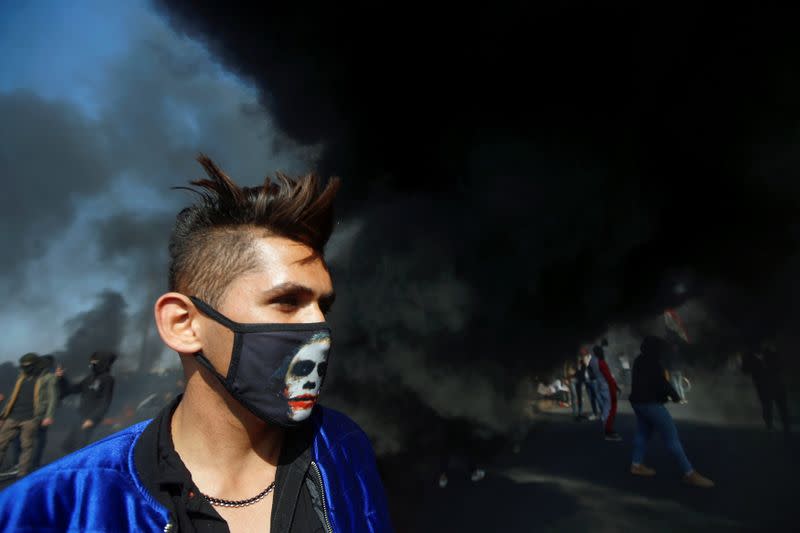 An Iraqi demonstrator is seen near burnt tires during ongoing anti-government protests in Basra