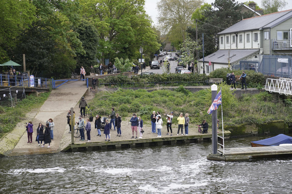 People gather at Teddington Lock to try and spot a Minke whale, which was freed on Sunday after it became stuck on Richmond lock's boat rollers but has remained in the Thames, is seen near Teddington Lock in London, Monday, May 10, 2021. A Port of London Authority spokesperson said a whale had never been seen this far up the Thames before, some 95 miles from its mouth. (Yui Mok/PA via AP)