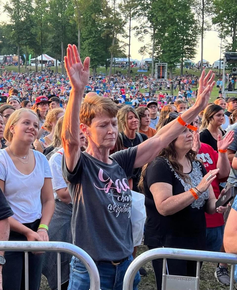 Darla Eubanks of Canton reaches out with her arms during Danny Gokey's concert Thursday night at the Alive Music Festival at Atwood Lake Park.