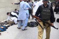 EDITORS NOTE: Graphic content / Plain cloth security personnel inspect recovered weapons next to a body of an alleged gunman outside the Pakistan Stock Exchange building in Karachi on June 29, 2020. - At least six people were killed after gunmen attacked the Pakistan Stock Exchange in Karachi on June 29, police said, with one policeman among the dead after the assailants opened fire and hurled a grenade at the trading floor. (Photo by Asif HASSAN / AFP) (Photo by ASIF HASSAN/AFP via Getty Images)