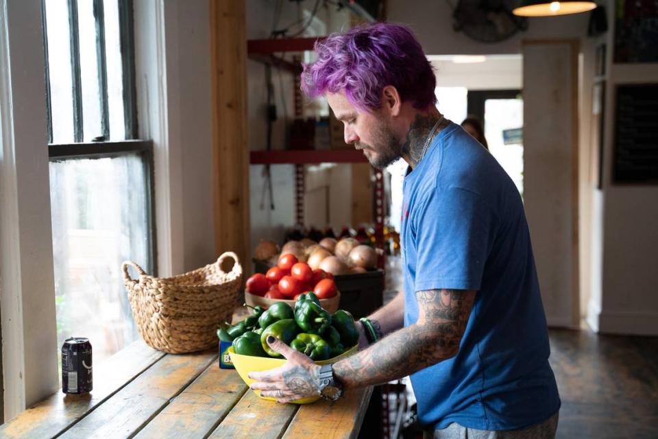 Joey Hewell sets out fresh vegetables before opening Noda Company Store + Grocery.