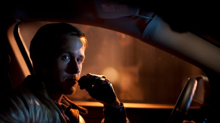 Ryan Gosling sits behind the wheel of a car.