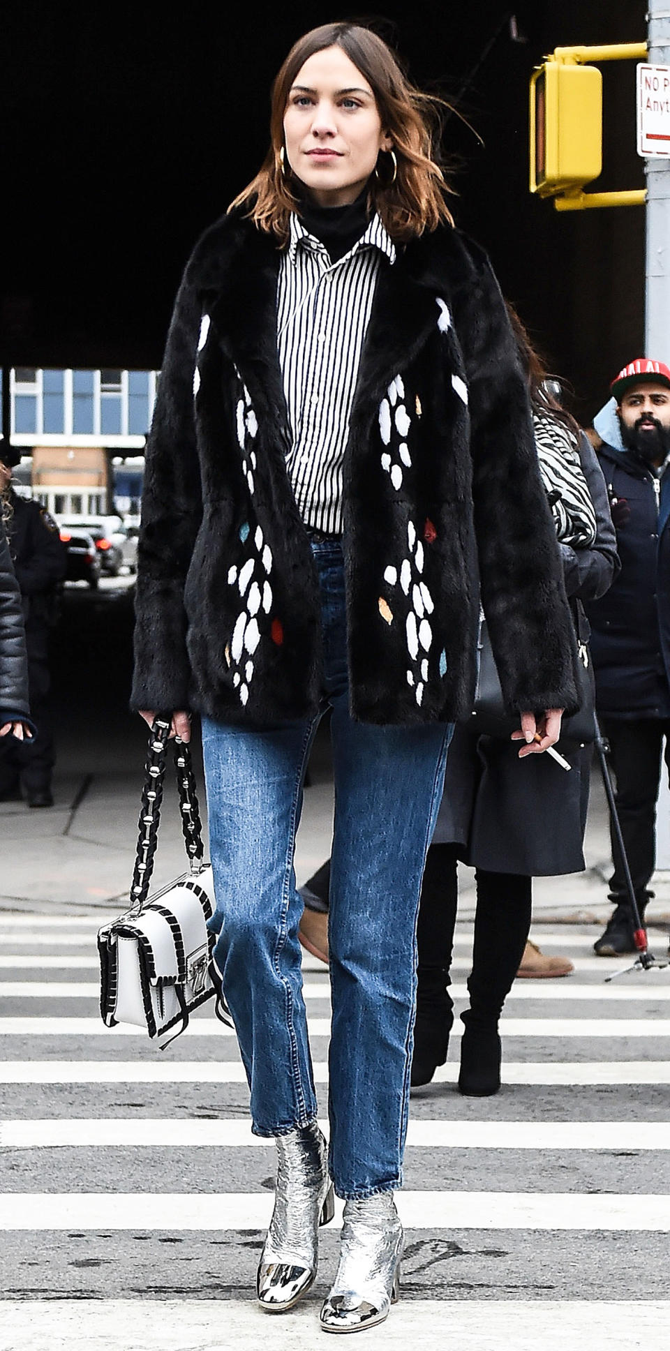 <p>Chung was spotted out and about during New York Fashion Week in a fur coat, striped button-down over a black turtleneck, blue jeans, and metallic booties (get a similar silver style <a rel="nofollow noopener" href="https://click.linksynergy.com/fs-bin/click?id=93xLBvPhAeE&subid=0&offerid=390098.1&type=10&tmpid=8157&RD_PARM1=http%253A%252F%252Fshop.nordstrom.com%252Fs%252Fpour-la-victoire-winona-boot-women%252F4447763%253Forigin%253Dcategory-personalizedsort%2526fashioncolor%253DSILVER%252520LEATHER&u1=ISAlexaChung3.22JA" target="_blank" data-ylk="slk:here;elm:context_link;itc:0;sec:content-canvas" class="link ">here</a>). She completed her look with a black and white structured bag and hoop earrings. </p>