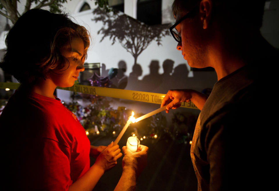 Olina Ortega, left, and Austin Gibbs light candles at a sidewalk memorial in front of Emanuel AME Church where people were killed by a white gunman Wednesday during a prayer meeting inside the historic black church in Charleston, S.C., Thursday, June 18, 2015. (AP Photo/David Goldman)