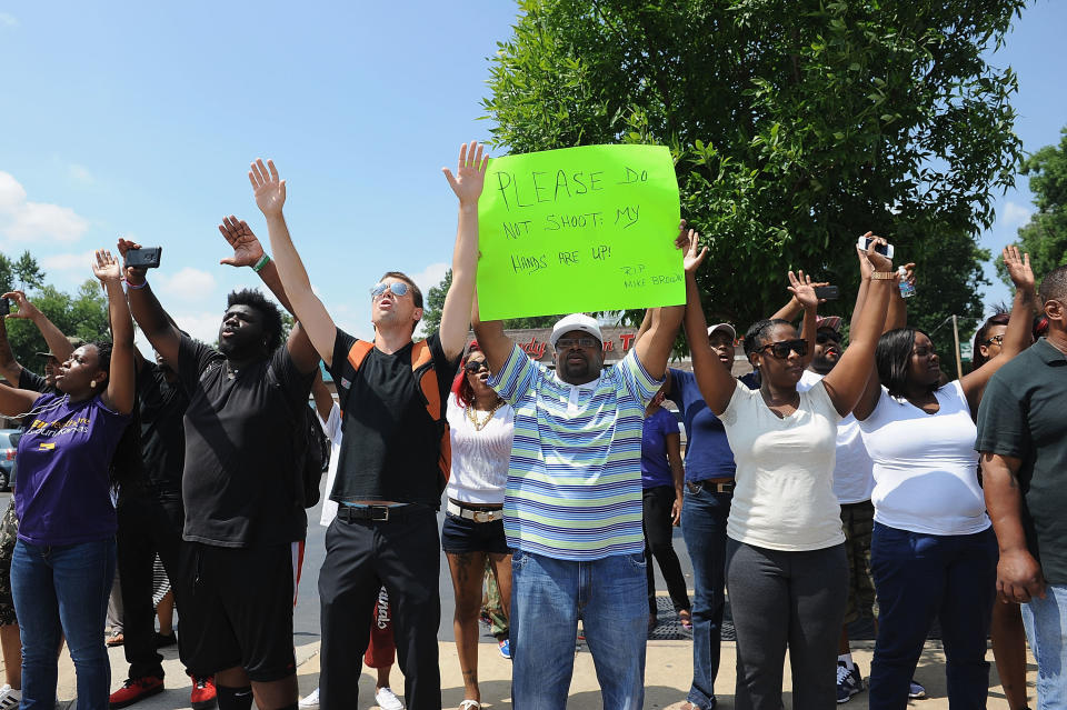 FERGUSON, MO - AUGUST 11:  Protestors stand with arms in the air during a protest of the shooting death of 18-year-old Michael Brown by a Ferguson police officer, outside Ferguson Police Department Headquarters August 11, 2014 in Ferguson, Missouri.  Civil unrest broke out as a result of the shooting of the unarmed black man as crowds looted and burned stores, vandalized vehicles and taunted police officers. Dozens were arrested for various infractions including assault, burglary and theft.  (Photo by Michael B. Thomas/Getty Images)