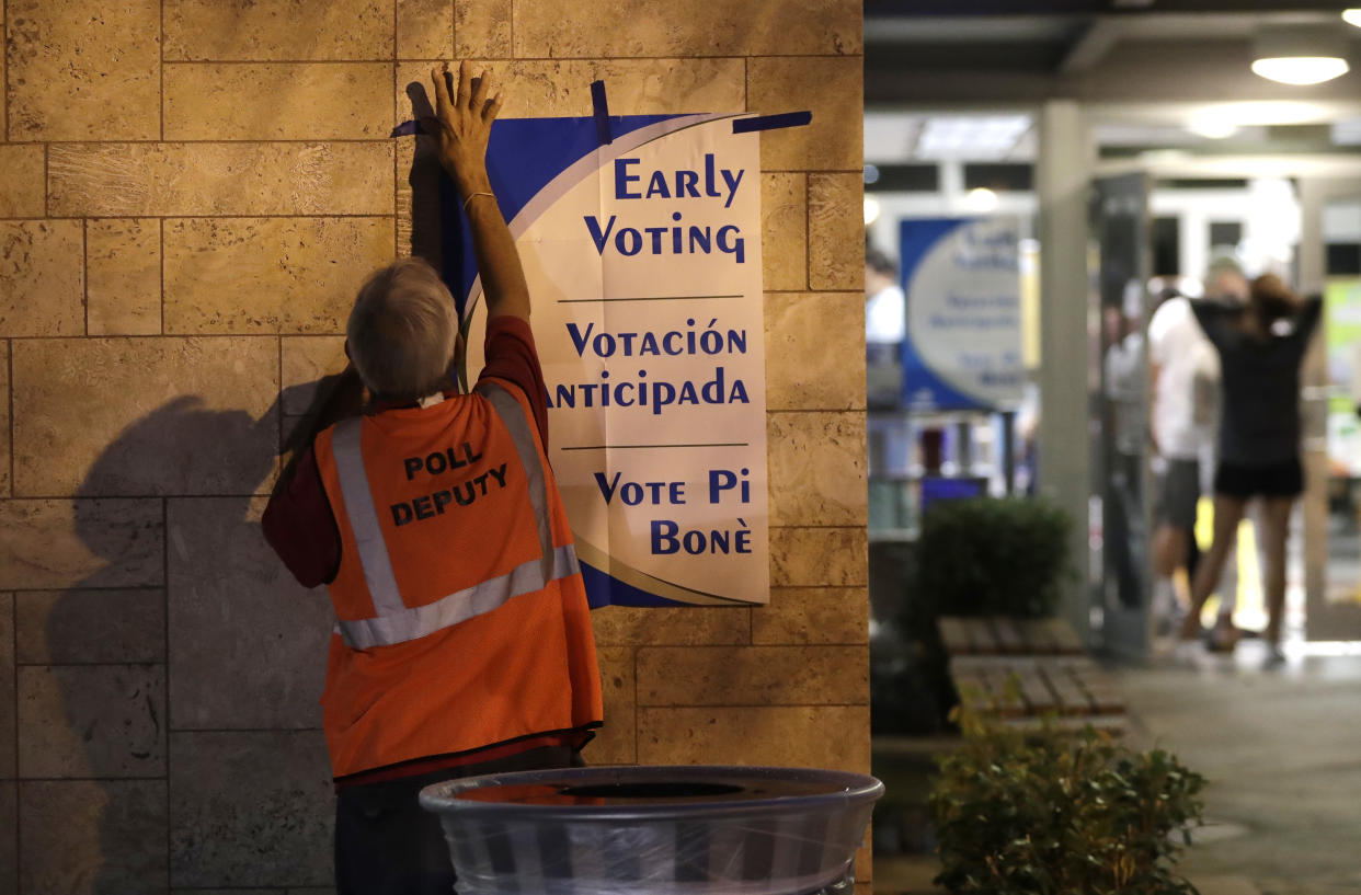 A poll worker hangs a sign at a polling station on Oct. 22, 2018, the first day of early voting in Miami-Dade County. (Photo: Lynne Sladky/AP)