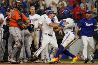 Texas Rangers' Corey Ragsdale, center, restrains Adolis Garcia, right, after Garcia was hit by a pitch thrown by Houston Astros' Bryan Abreu during the eighth inning in Game 5 of the baseball American League Championship Series Friday, Oct. 20, 2023, in Arlington, Texas. (AP Photo/Julio Cortez)