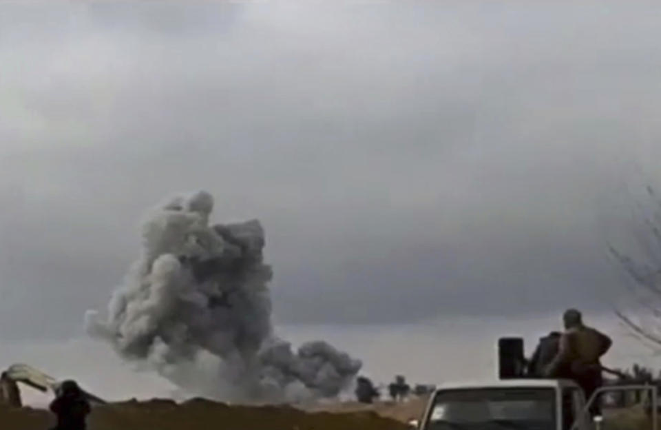 This frame grab from video provided on Tuesday, Feb. 12, 2019, by the Syrian Observatory for Human Rights, an opposition group, that is consistent with independent AP reporting, shows U.S.-backed Syrian Democratic Forces fighters looking at smoke rising from a shell that targeted Islamic State group militants, in the village of Baghouz, Deir El-Zour, eastern Syria. Fighting between U.S.-backed fighters and IS inflicted more casualties among people fleeing the violence in eastern Syria Tuesday where the extremists are on the verge of losing the last area they control. (Syrian Observatory for Human Rights via AP)