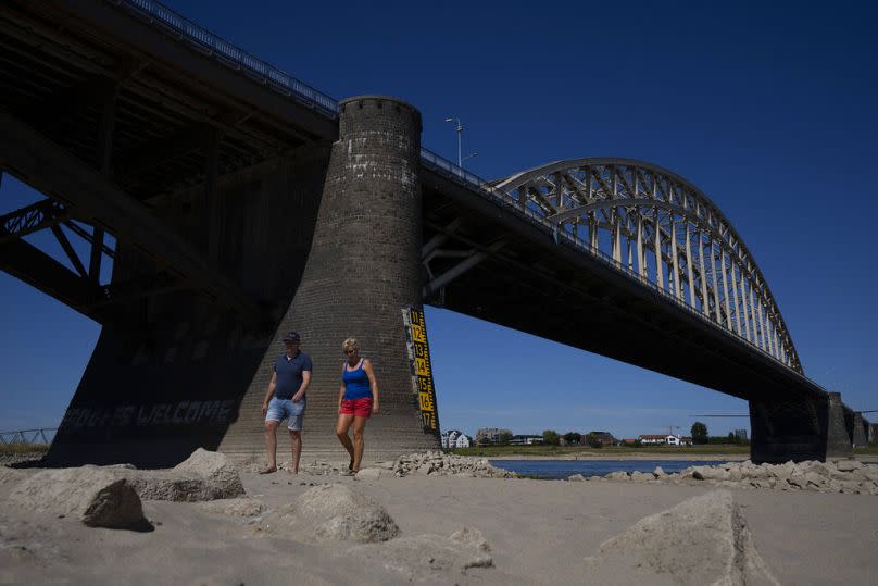 ARCHIVO - Un grupo de personas pasea por el cauce del río Waal debido a la sequía en Nimega, Países Bajos, el martes 9 de agosto de 2022.