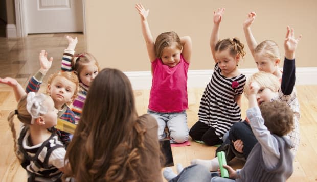 Children (2-3, 4-5) sitting on floor and raising hands