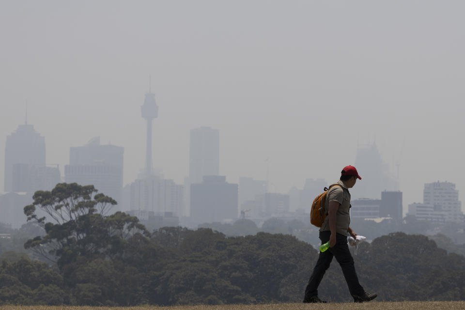 Smoke blankets the Sydney CBD as a man walks by in a cap and jeans.