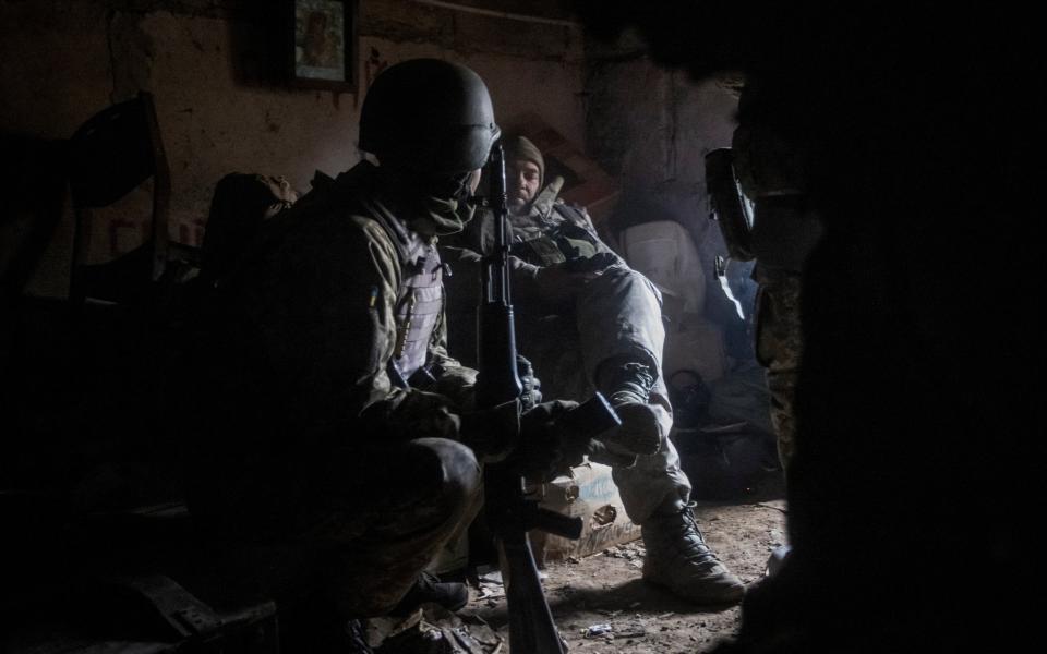 Two soldiers sit in a dark bunker - REUTERS/Yevhen Titov