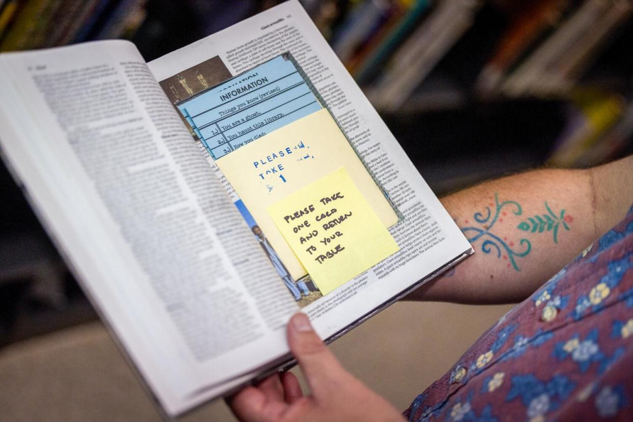 A person holding a book open to reveal clues hidden inside it.